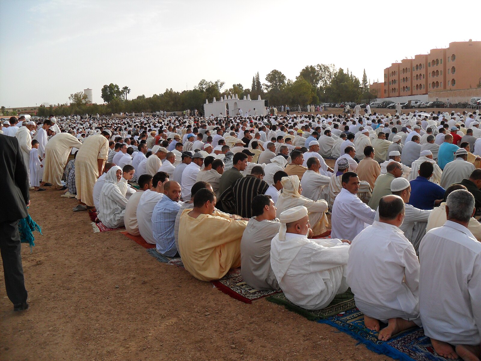 An open-air Eid al-Fitr morning prayer in Morocco, with rows of worshippers facing the qibla.