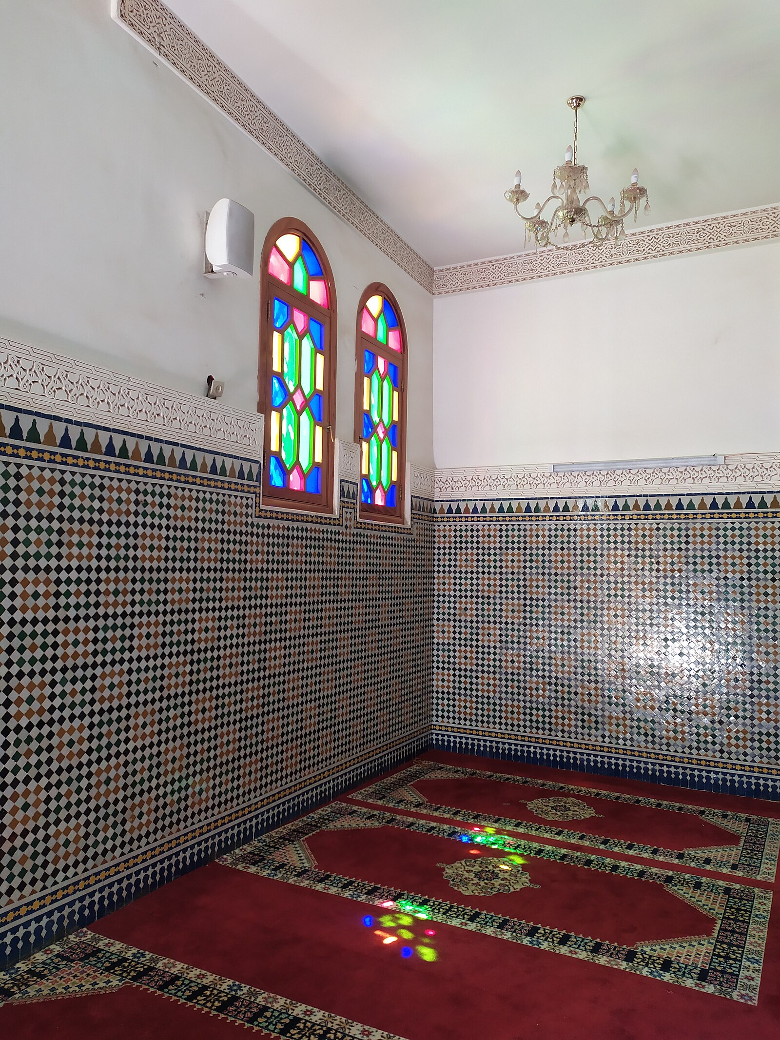 Interior of a mosque in Oujda, eastern Morocco, with patterned green carpet and arched colonnades.