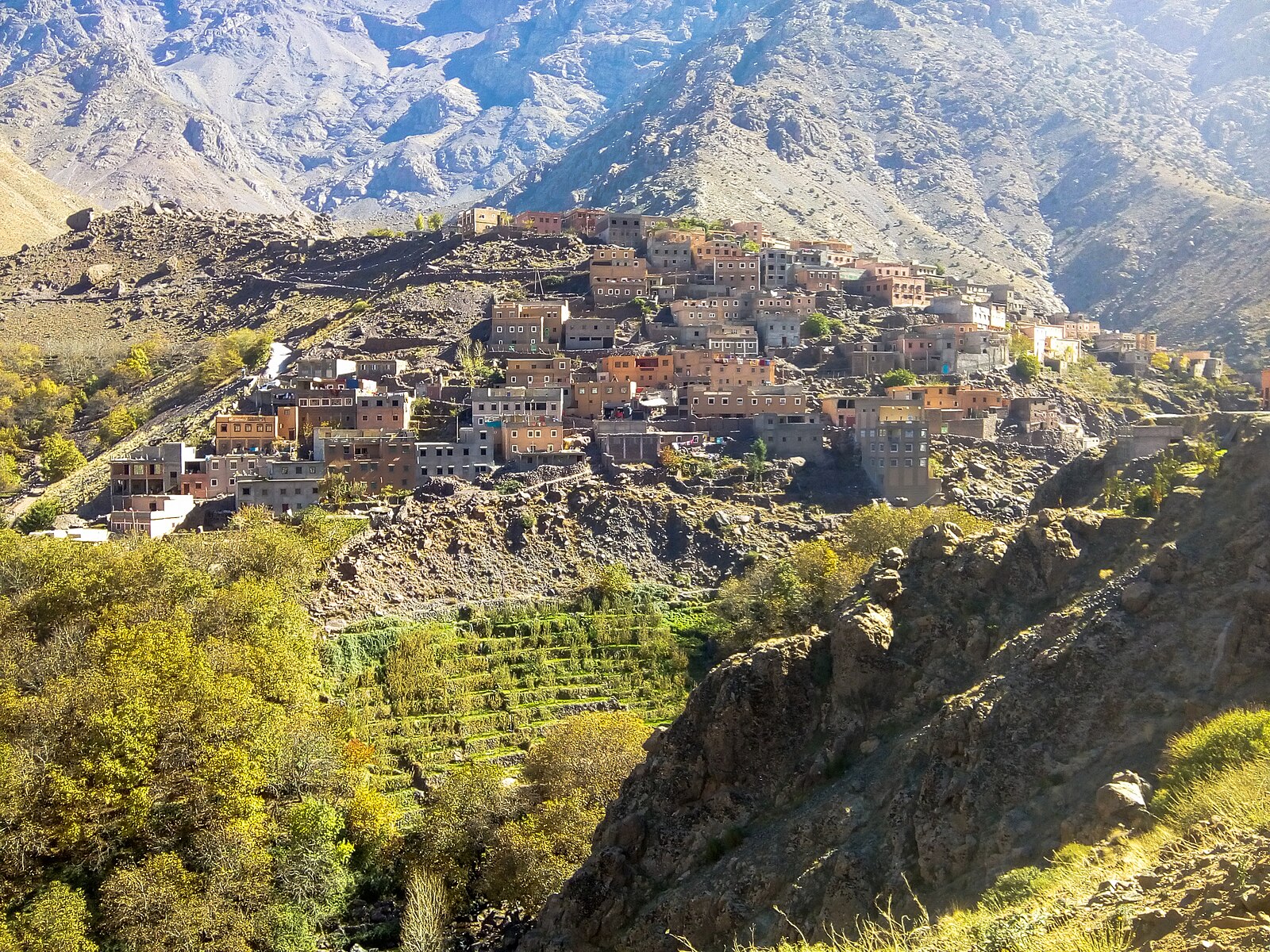 Imlil village in the High Atlas mountains of Morocco, with stone houses, terraced fields, and snow-capped peaks behind.