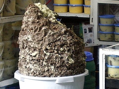 A jar of khlea, traditional Moroccan sun-dried and spiced preserved beef, on a kitchen counter.