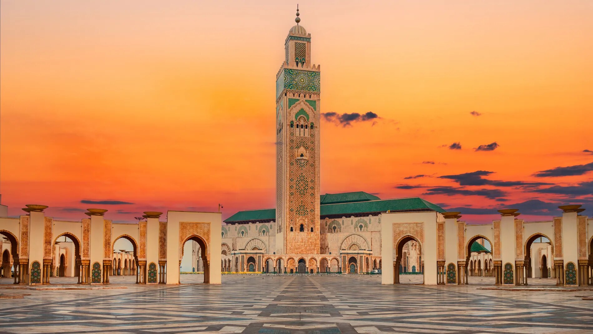 The Hassan II Mosque in Casablanca at sunset, courtyard and colonnade flanking the central minaret.